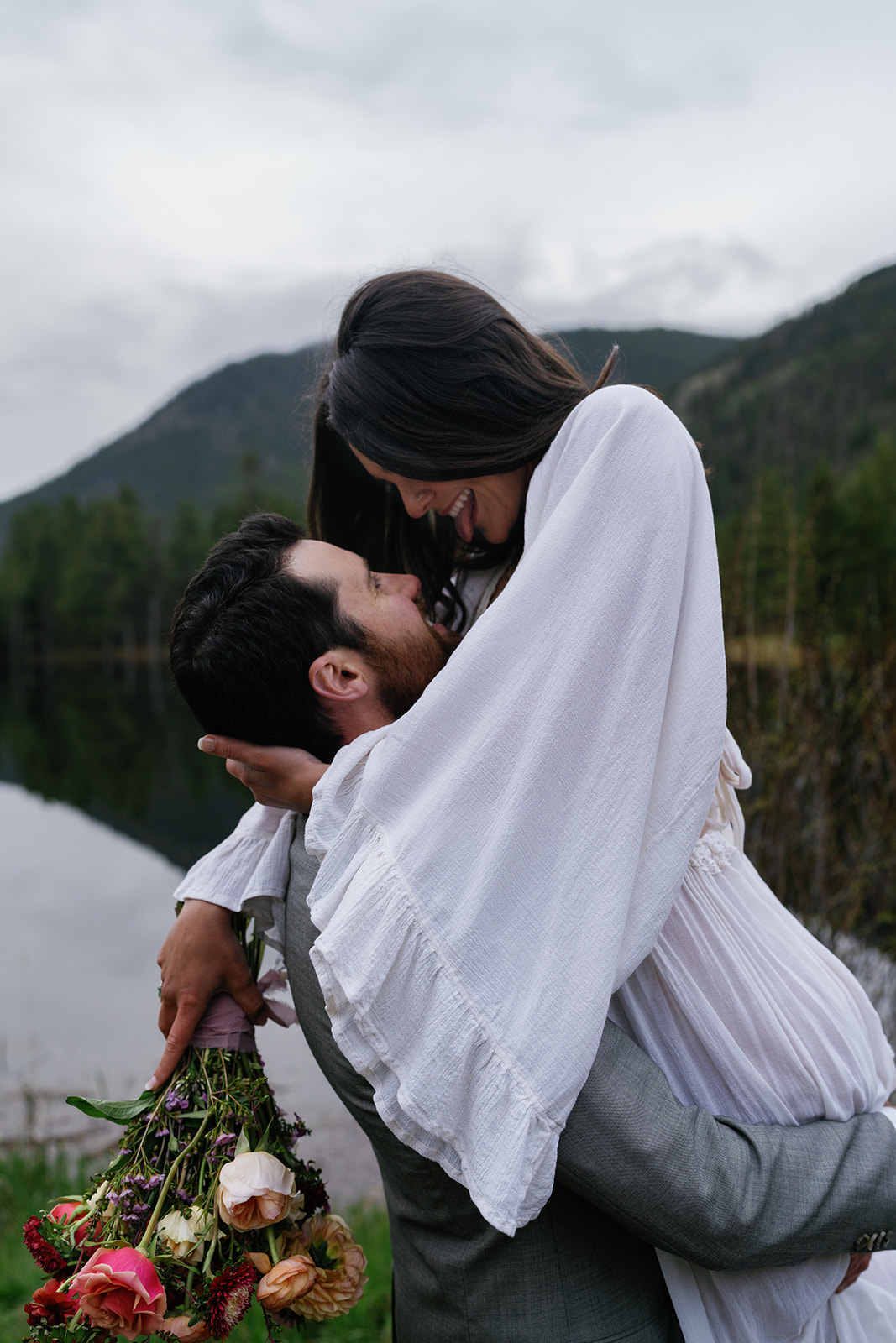 A groom lifts his new bride while standing in the snow in the mountains Blue lakes Breckenridge Elopement