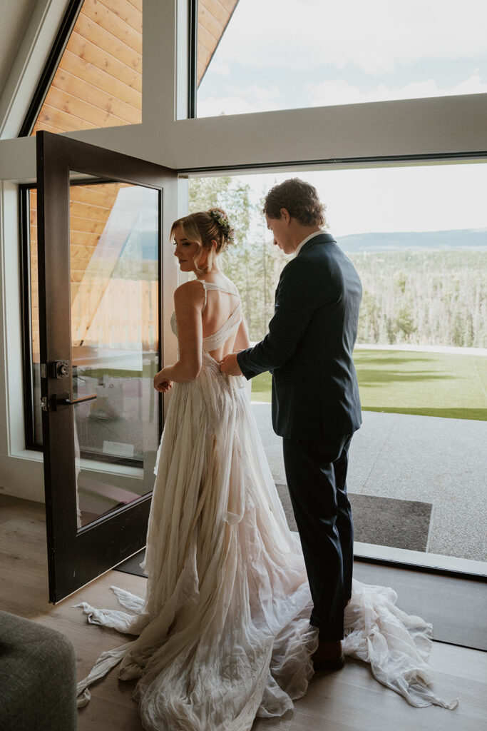 Groom helping his bride into her elopement dress