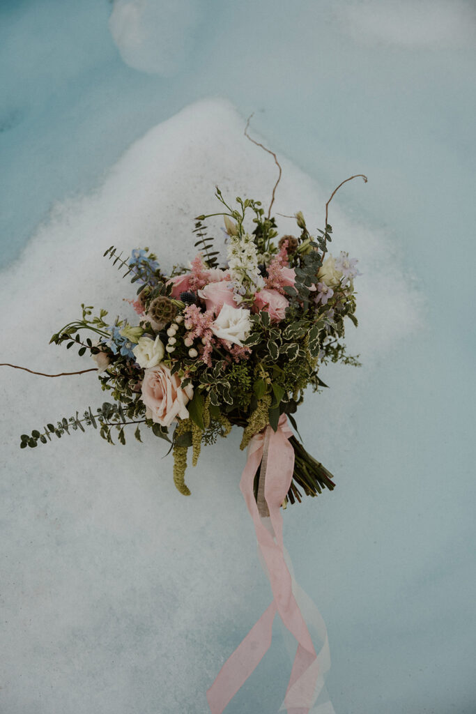 Brides wedding bouquet laying on a glacier at Knik Glacier from an Alaksa helicopter elopement