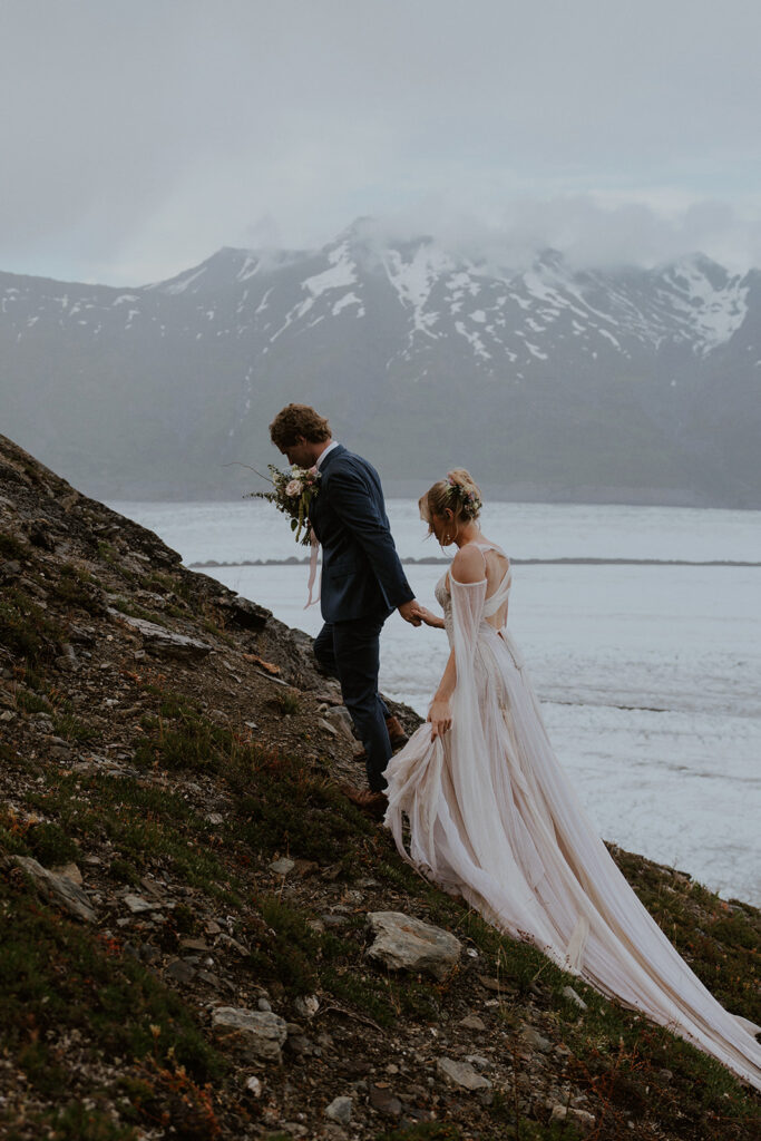 Bride and groom walking up a hill at Knik Glacier during their Alaska helicopter elopement