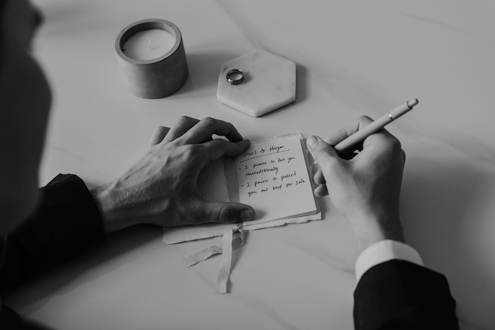 Black and white photo of a groom writing his vows to his bride