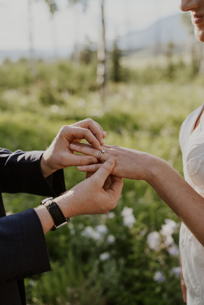 Groom putting a ring on his brides finger