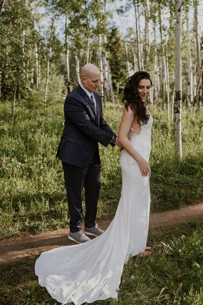 Groom helping his bride zip up her dress