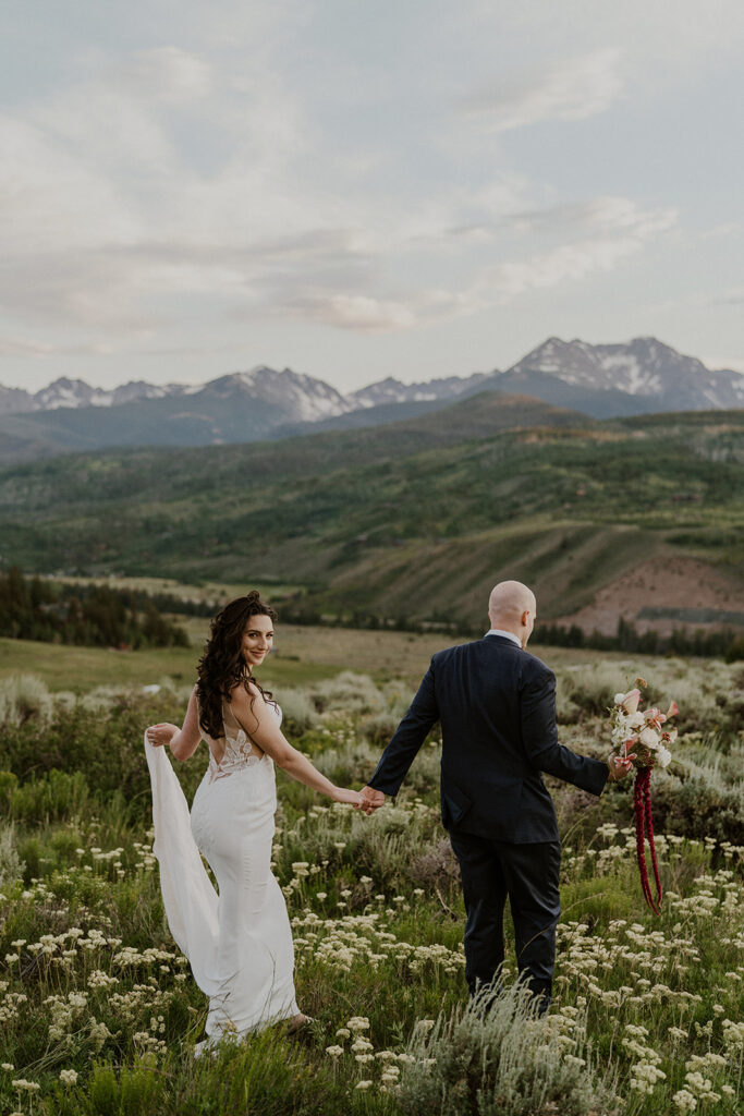 Bride and groom walking through a wildflower meadow for their Breckenridge Colorado elopement photos