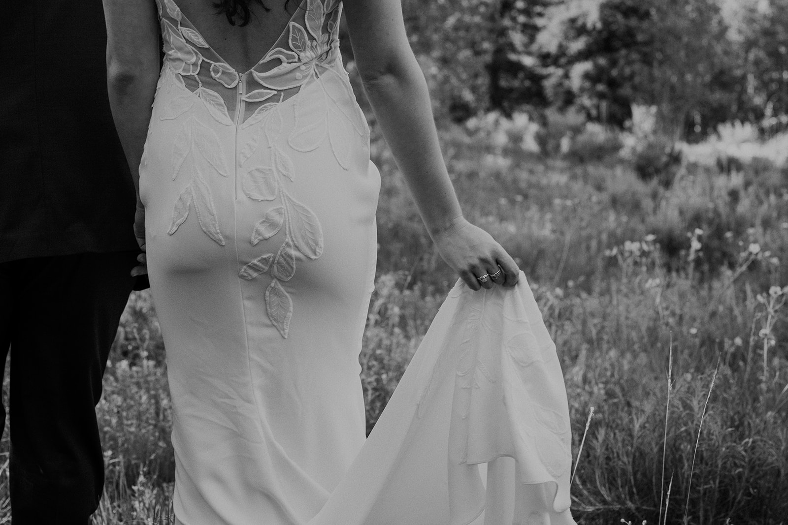 Close up black and white photo of a bride and groom walking through the Colorado mountains
