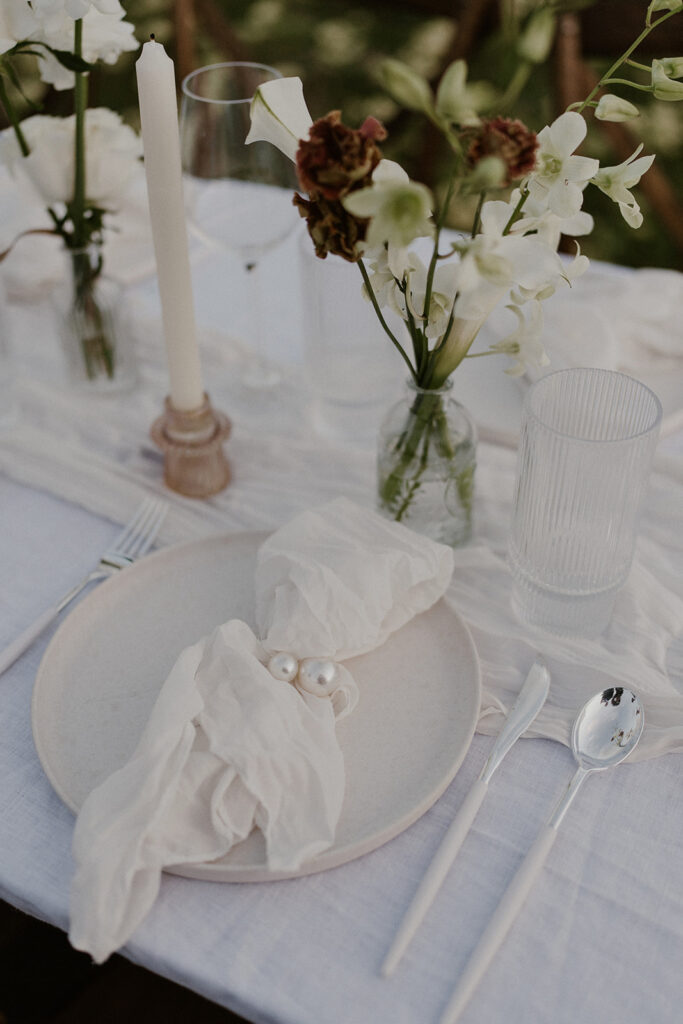 Minimalist place setting with a white plate, textured napkin, and floral centerpiece at the elopement tablescape.