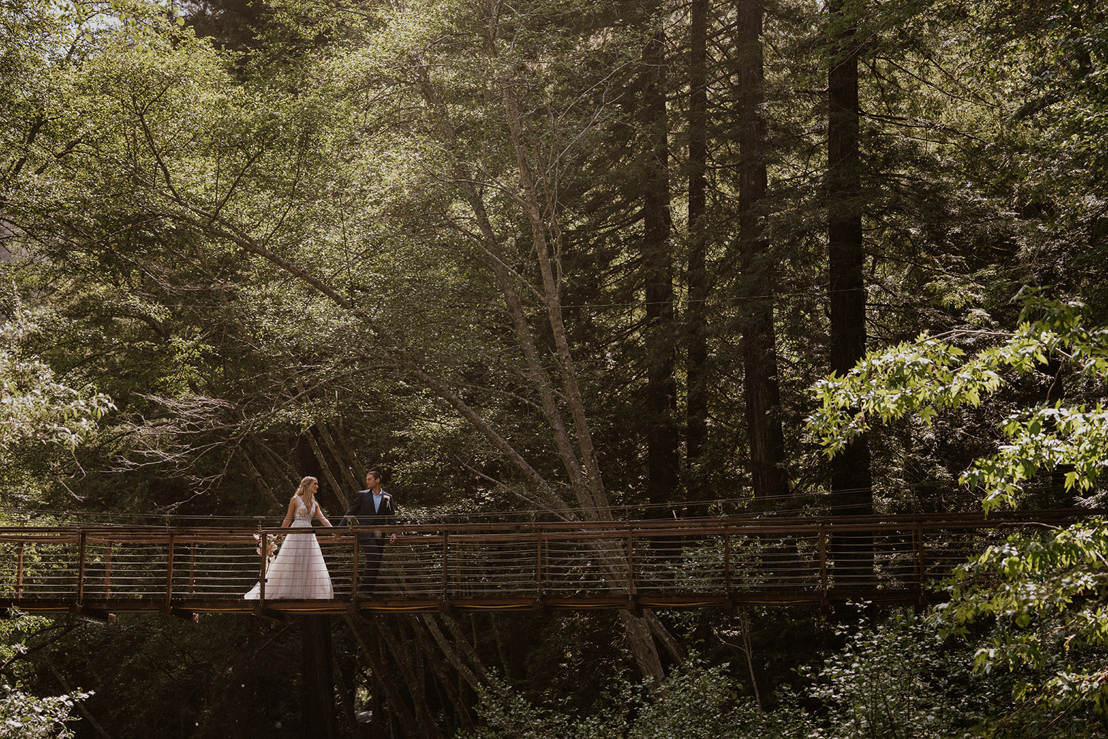 Bride and groom walking across a bridge during their Big Sur elopement photos