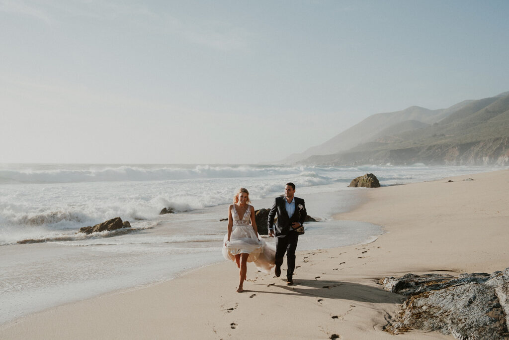 bride and groom running along the beach in Big Sur
