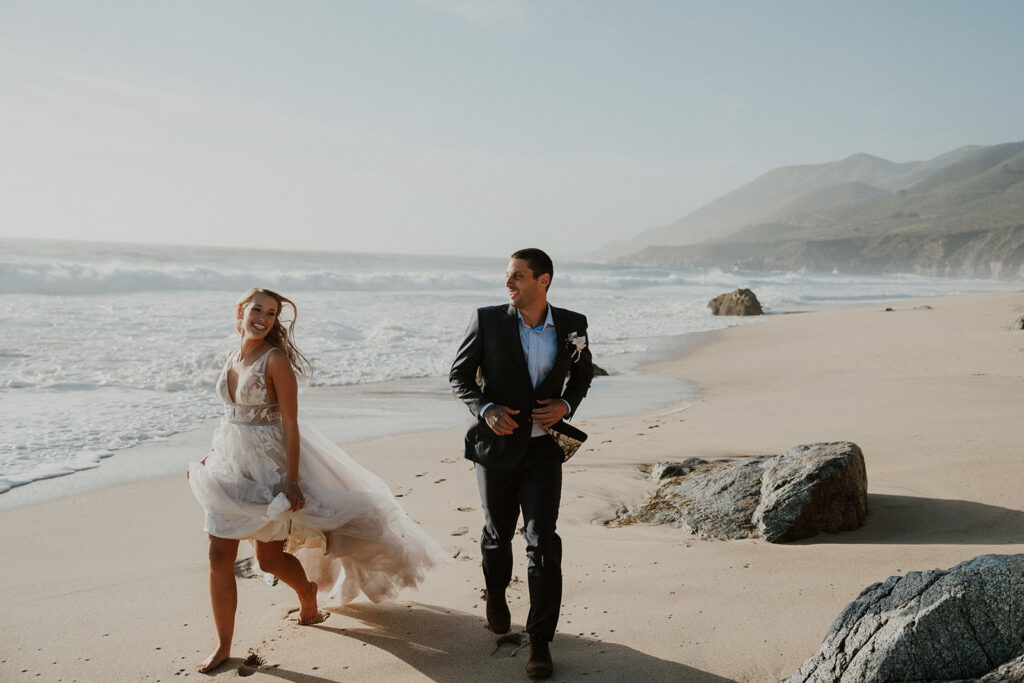 bride and groom running along the beach in Big Sur
