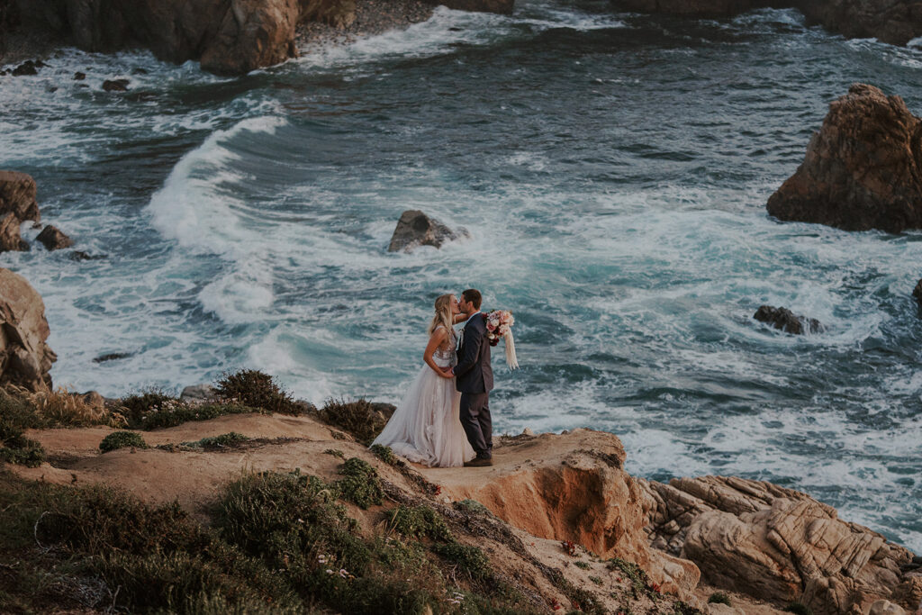 Bride and groom kissing cliffside