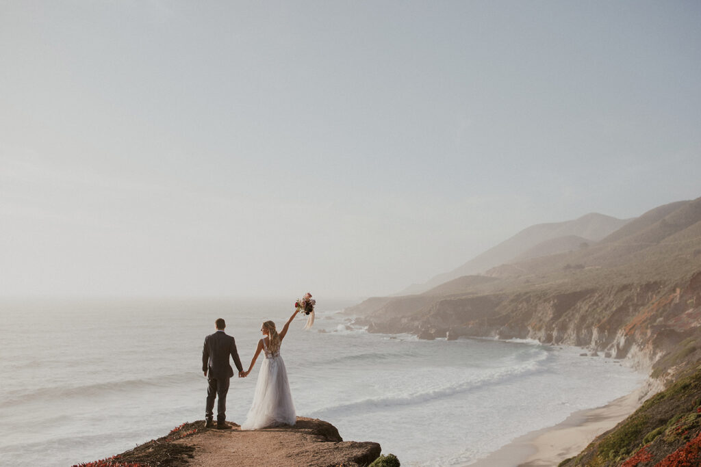 Bride and groom admiring the beach from a cliff