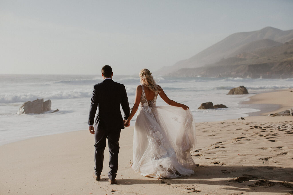 Bride and groom watching the waves crash onto the beach