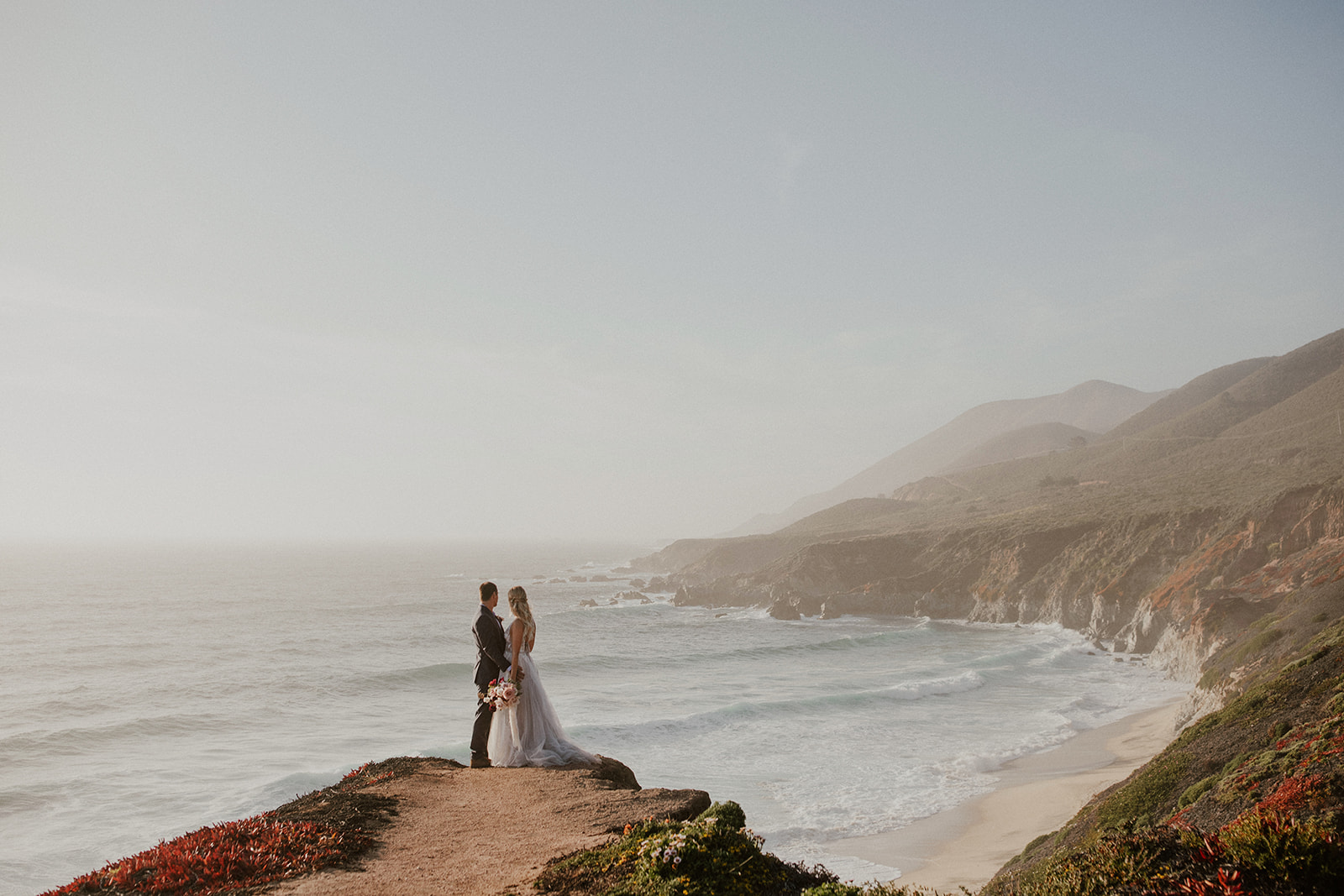 Bride and groom admiring the beach from a cliff
