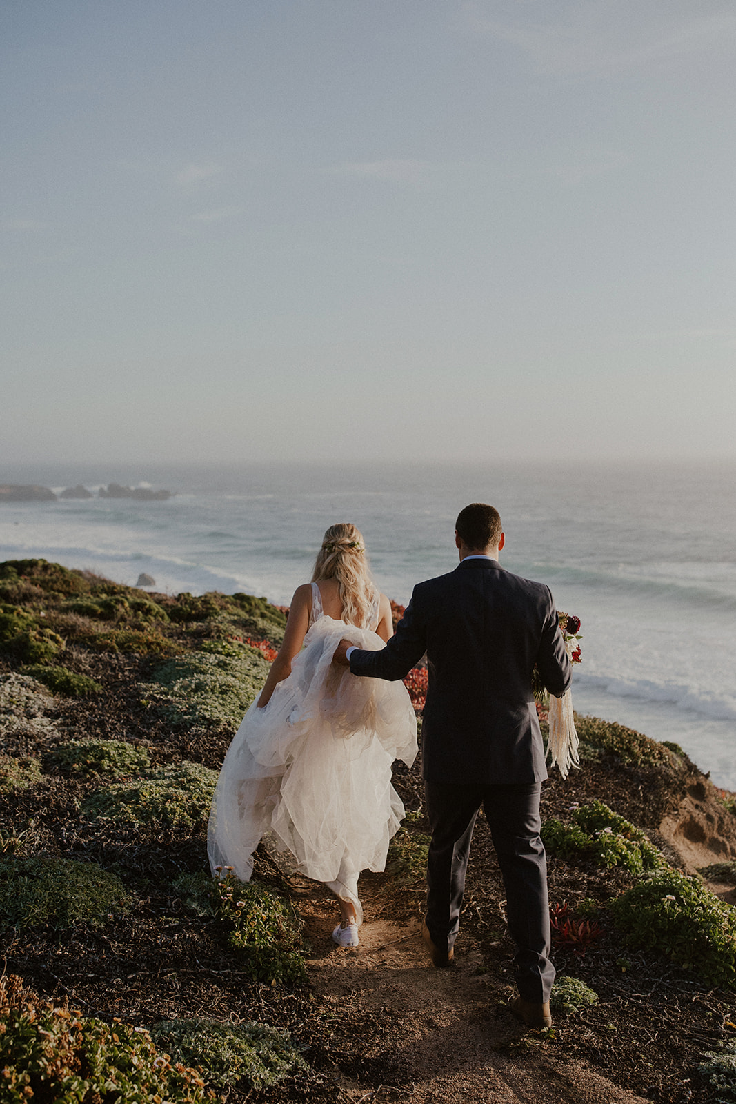 Bride and groom walking along the cliffs in Big Sur, California