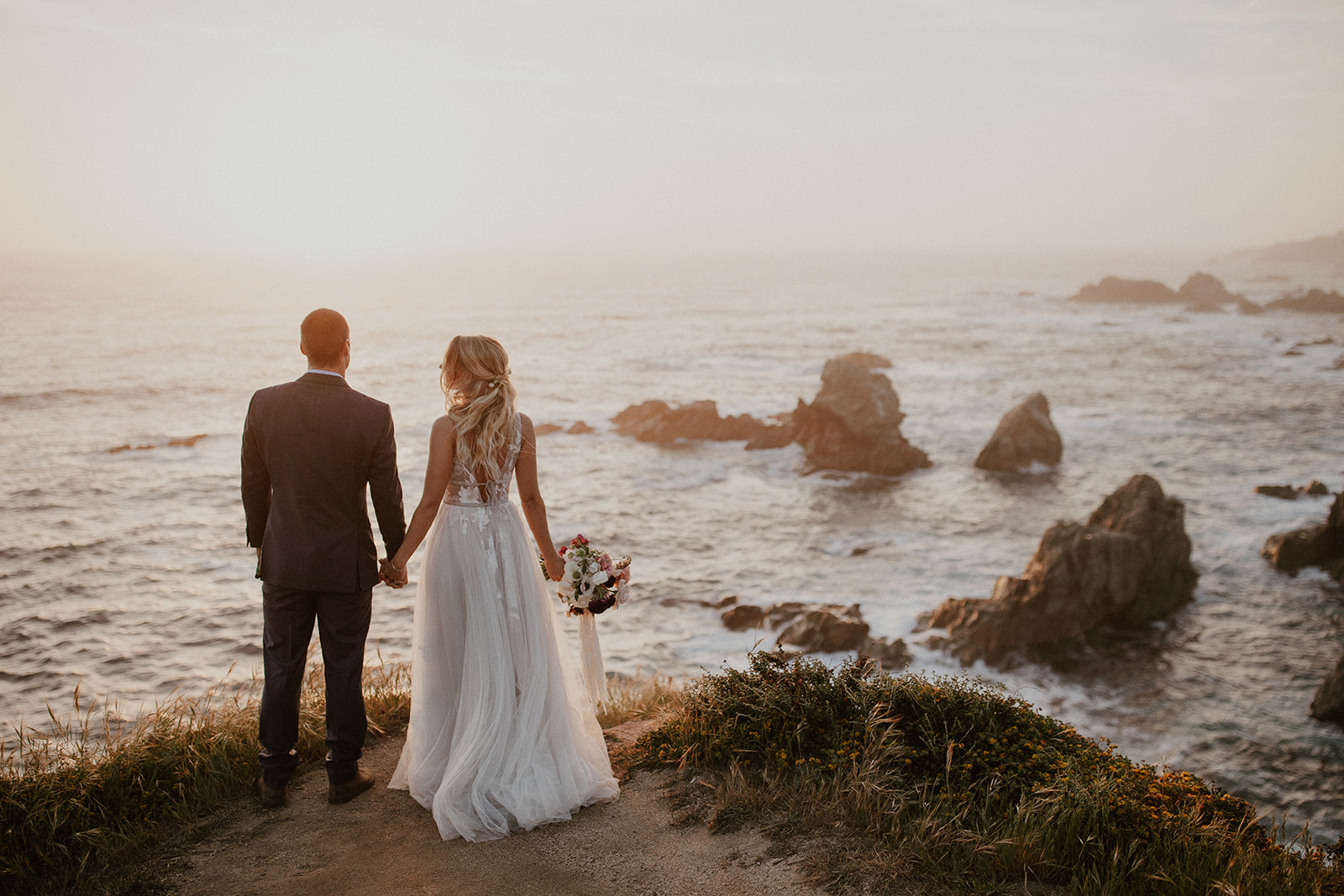 Bride and groom standing along the cliff during their sunset elopement in Big Sur, California