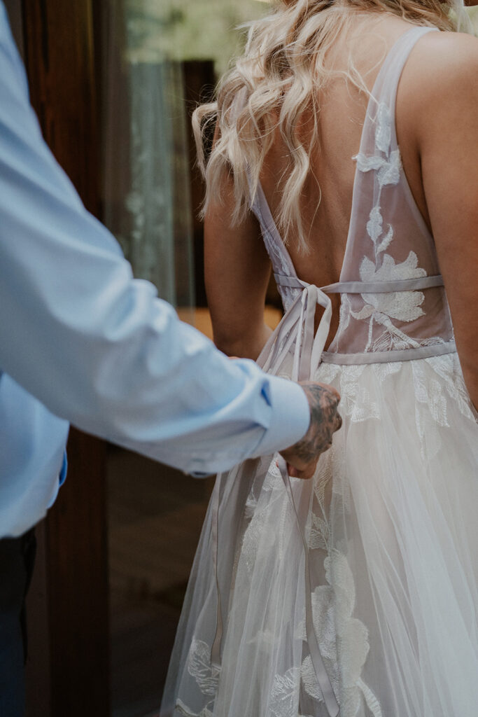 Groom helping his bride get ready fro their elopement
