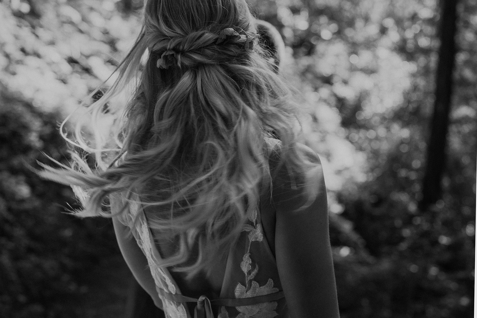 Black and white candid photo of a bride walking in the redwoods