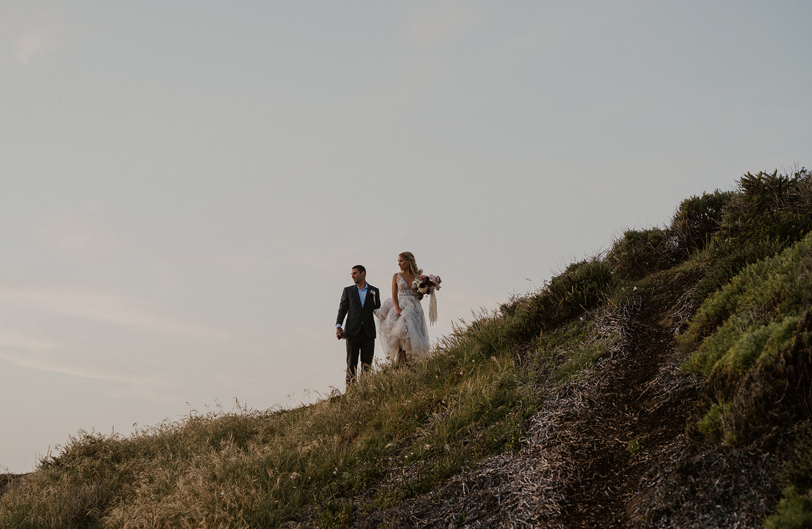 Bride and groom looking down the cliff