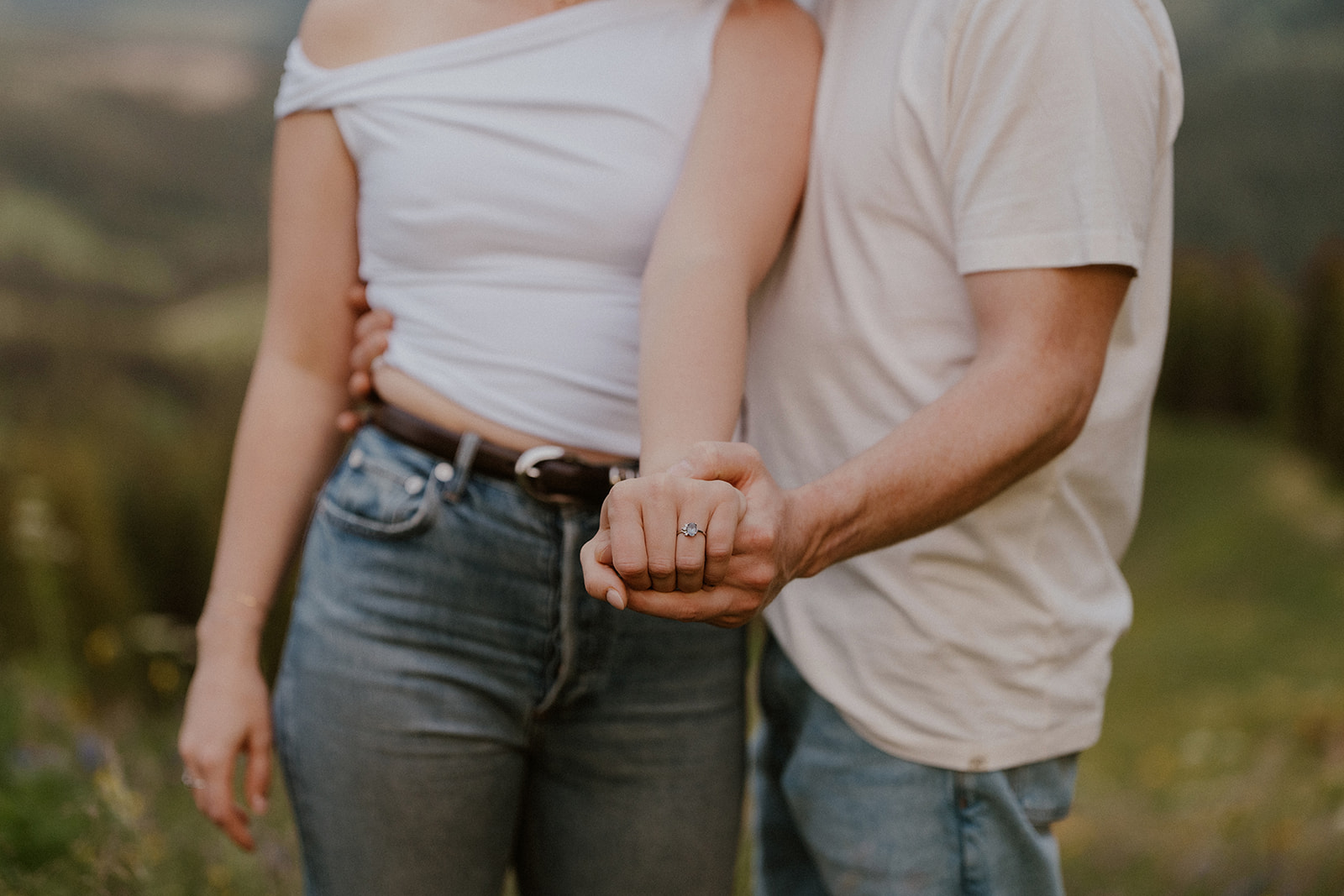 Couple showing off an engagement ring during their casual mountain engagement session