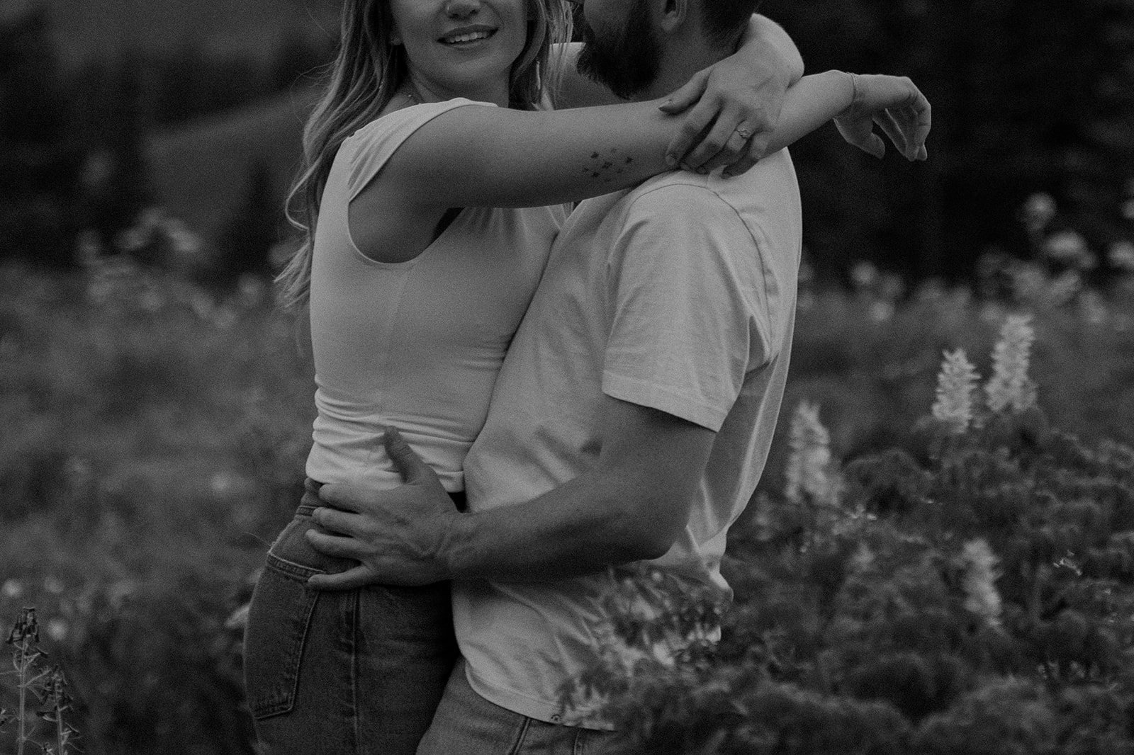 Black and white close up shot of a couple hugging each other in the wildflowers