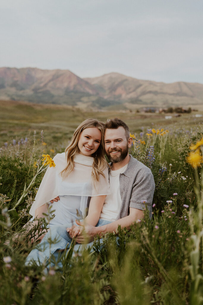 Couple sitting in the wildflowers during their Crested Butte engagement photos