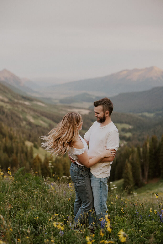 Couple wearing blue jeans and white shirts during their wildflower Crested Butte engagement photos
