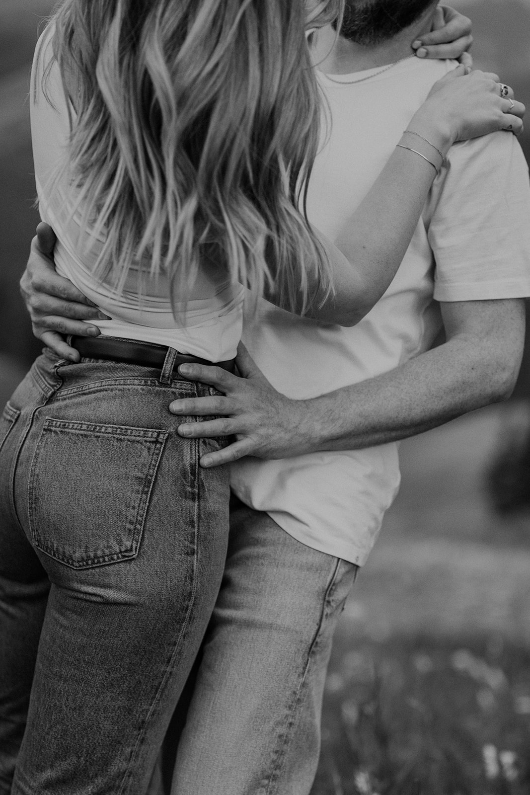 Close up black and white shot of a man holding onto his fiancés hips during their mountain engagement shoot
