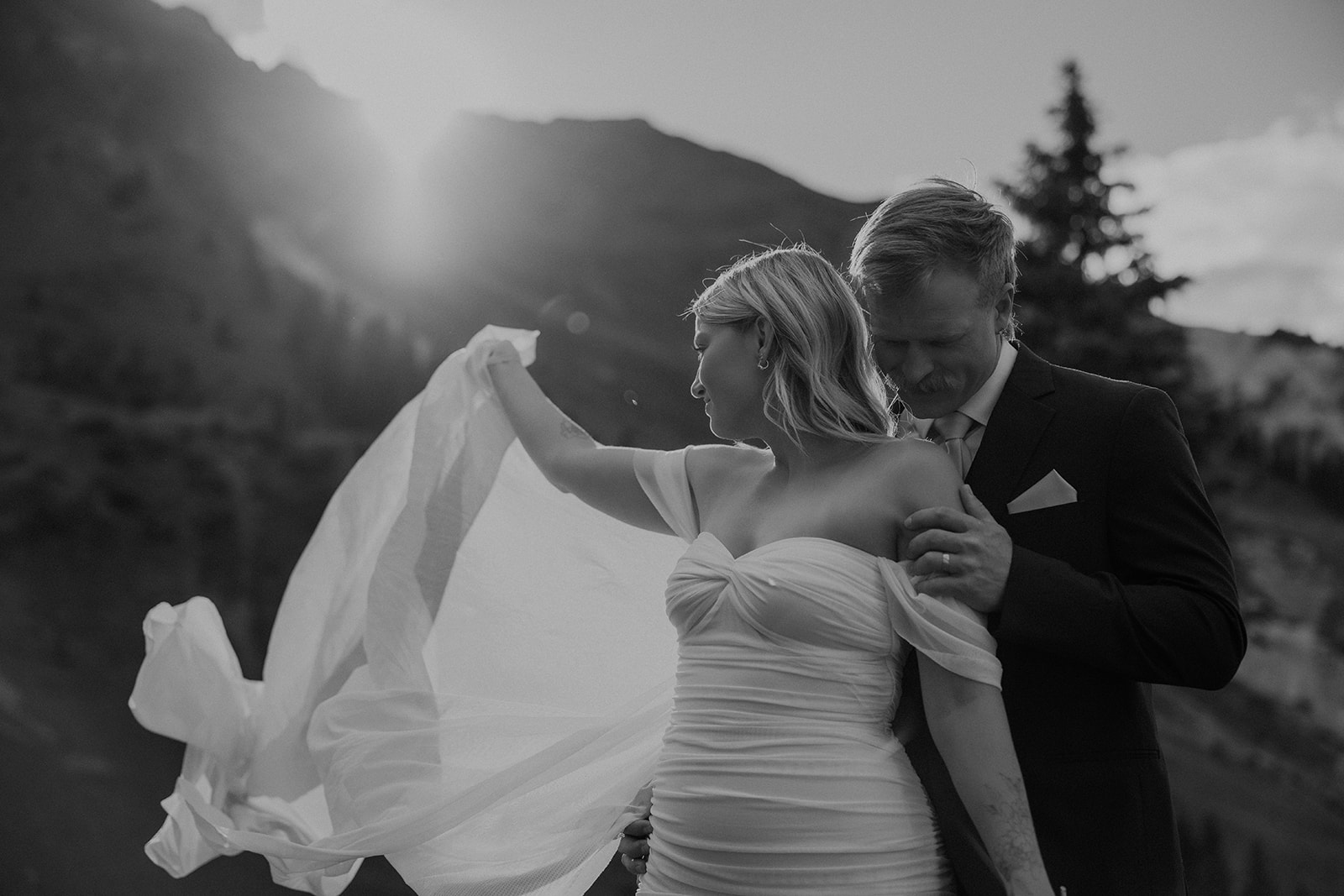 Black and white photo of a bride and groom posing in the mountains