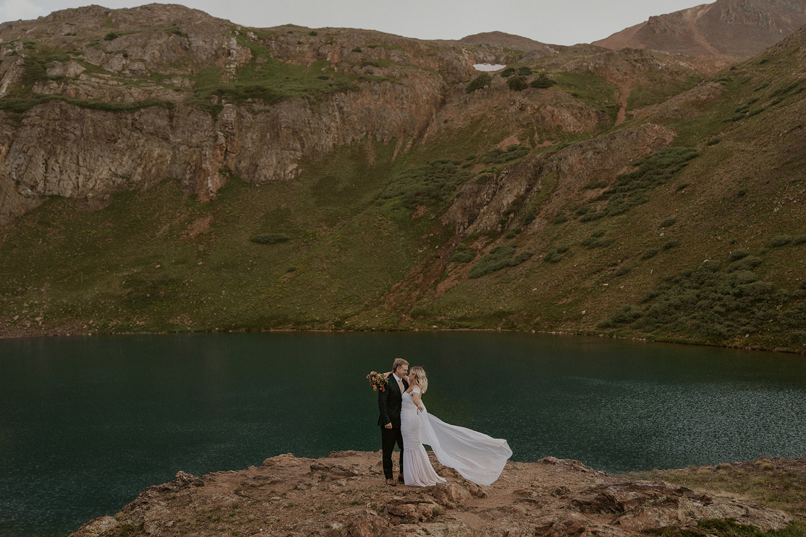 Bride and groom standing on a cliff in the San Juans