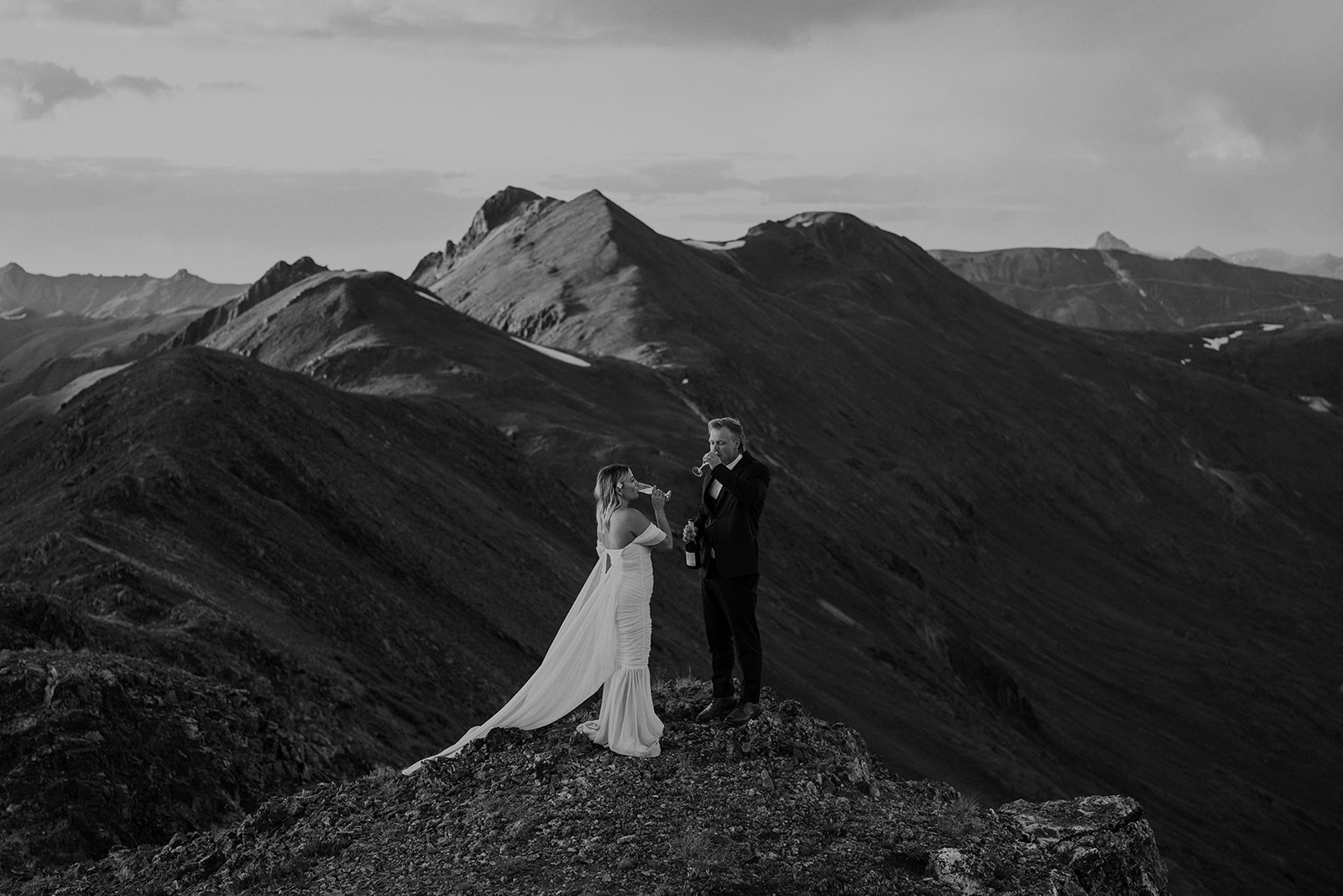 Black and white photo of a bride and groom drinking champagne during their San Juan mountains elopement photos in Colorado