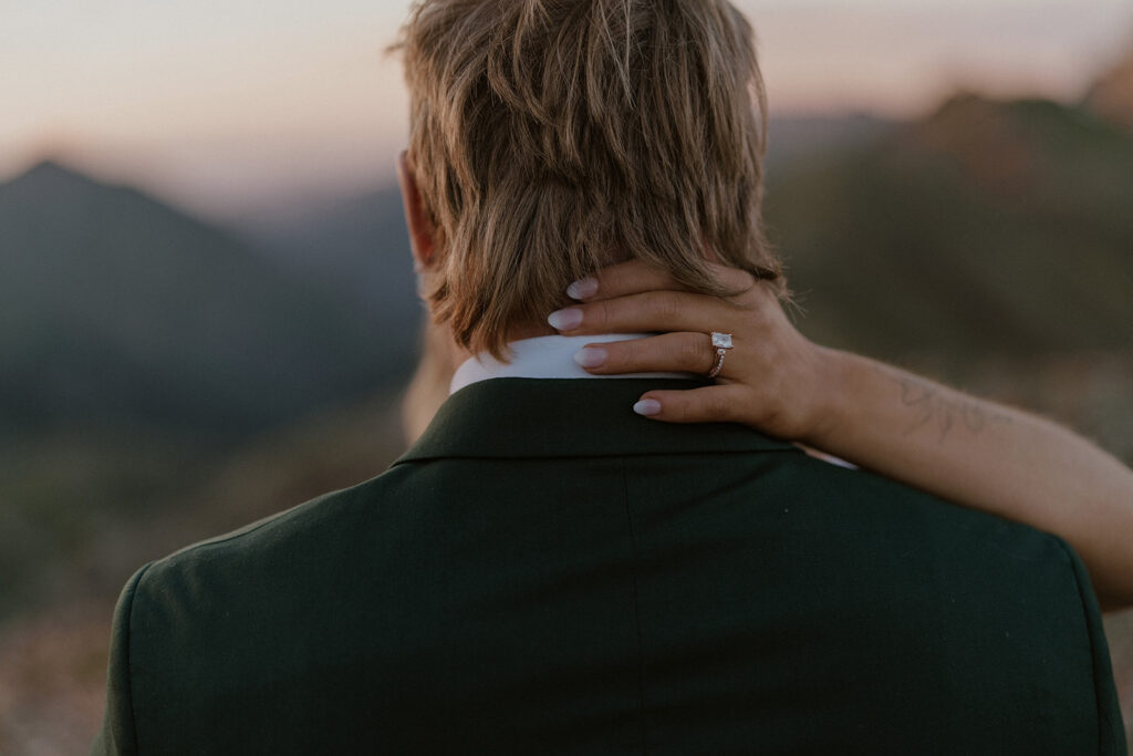 Close up shot of a bride with her hand caressing the back of her husbands neck and showing off her ring