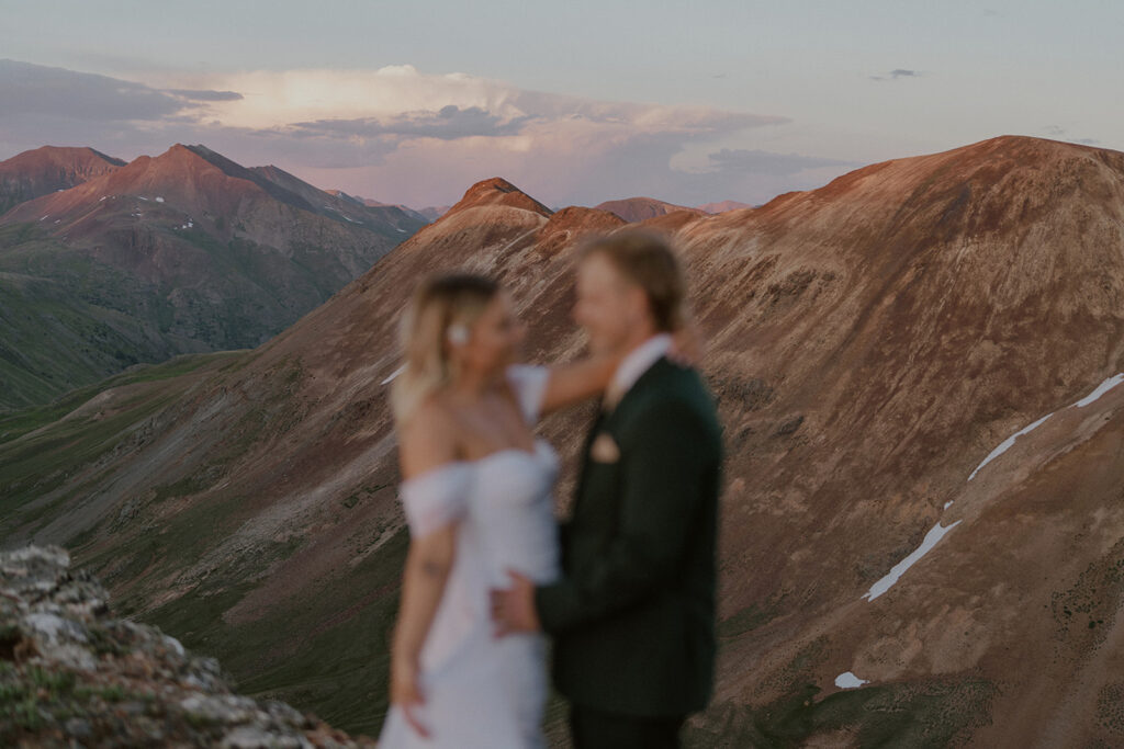 Out of focus photo of a bride and groom posing in the mountains