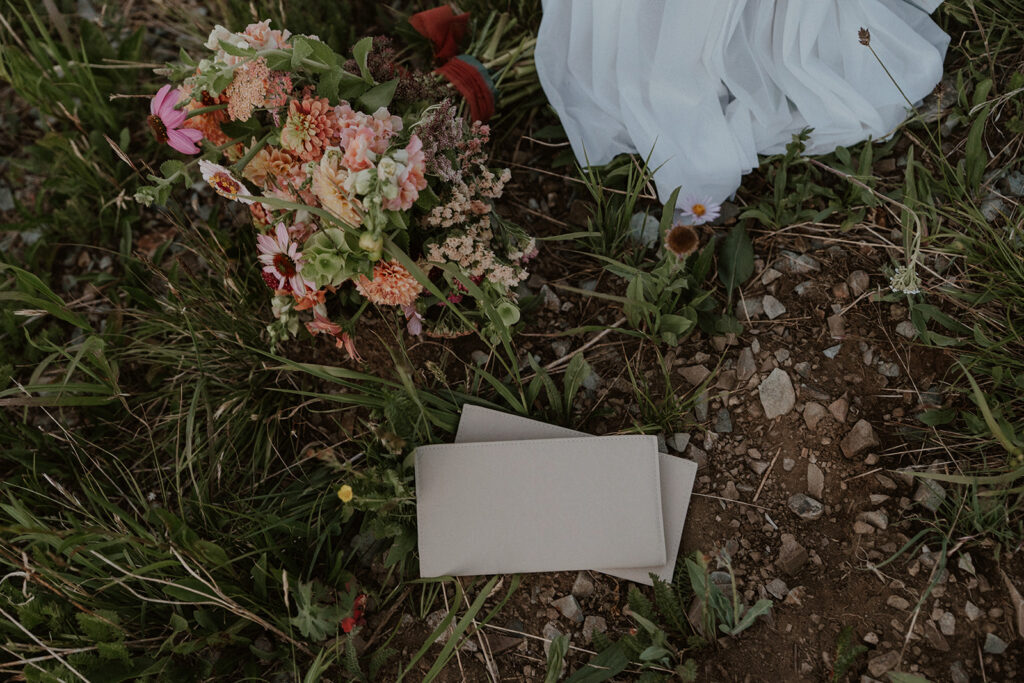 Close up shot of a brides bouquet and vow books in the grass