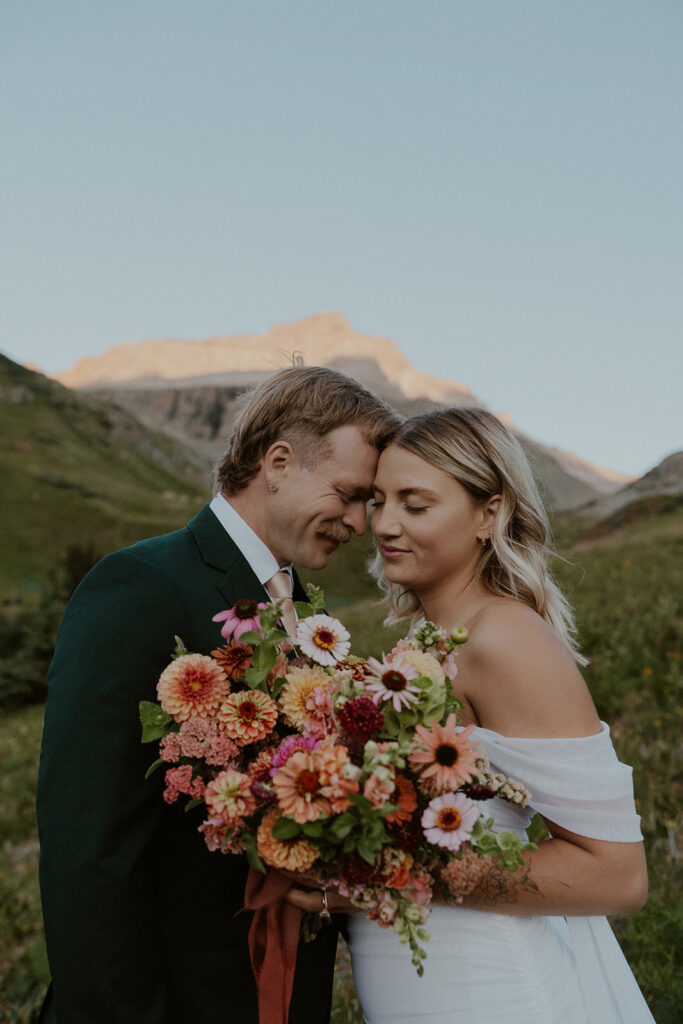 Bride and groom posing for their Colorado elopement photos with the San Juan mountains in the background