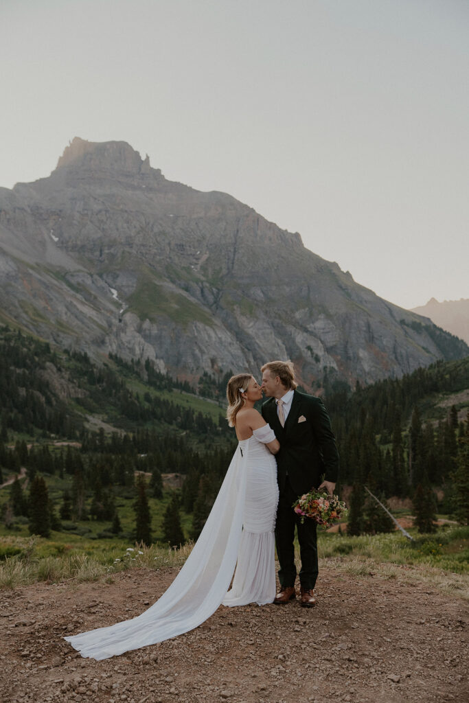 Bride and groom posing for their Colorado elopement photos with the San Juan mountains in the background