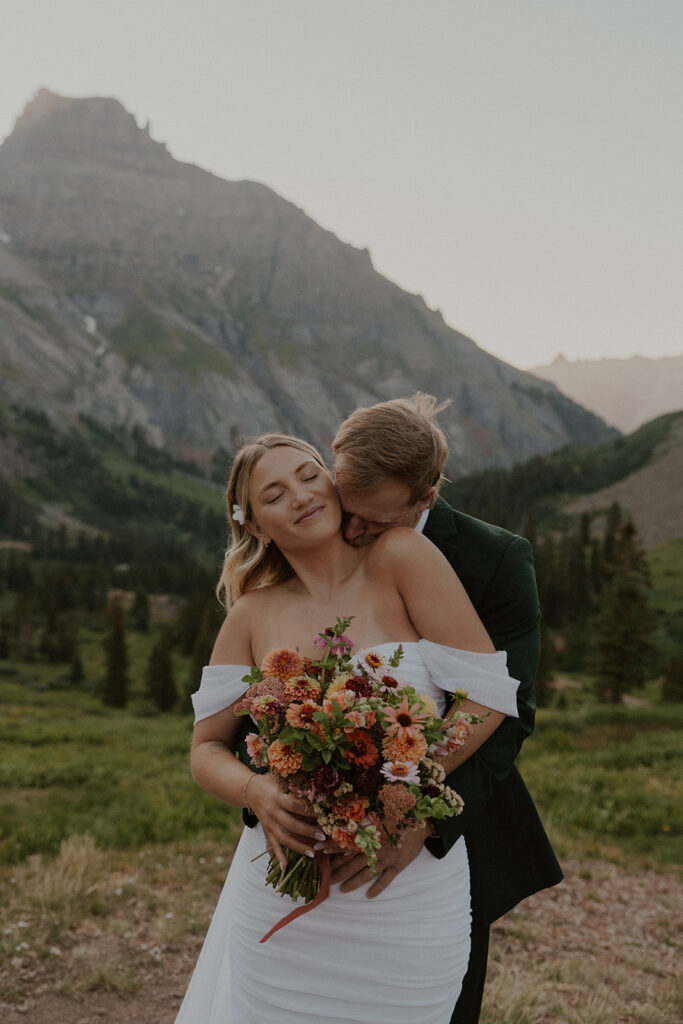 Bride and groom posing for their Colorado elopement photos with the San Juan mountains in the background