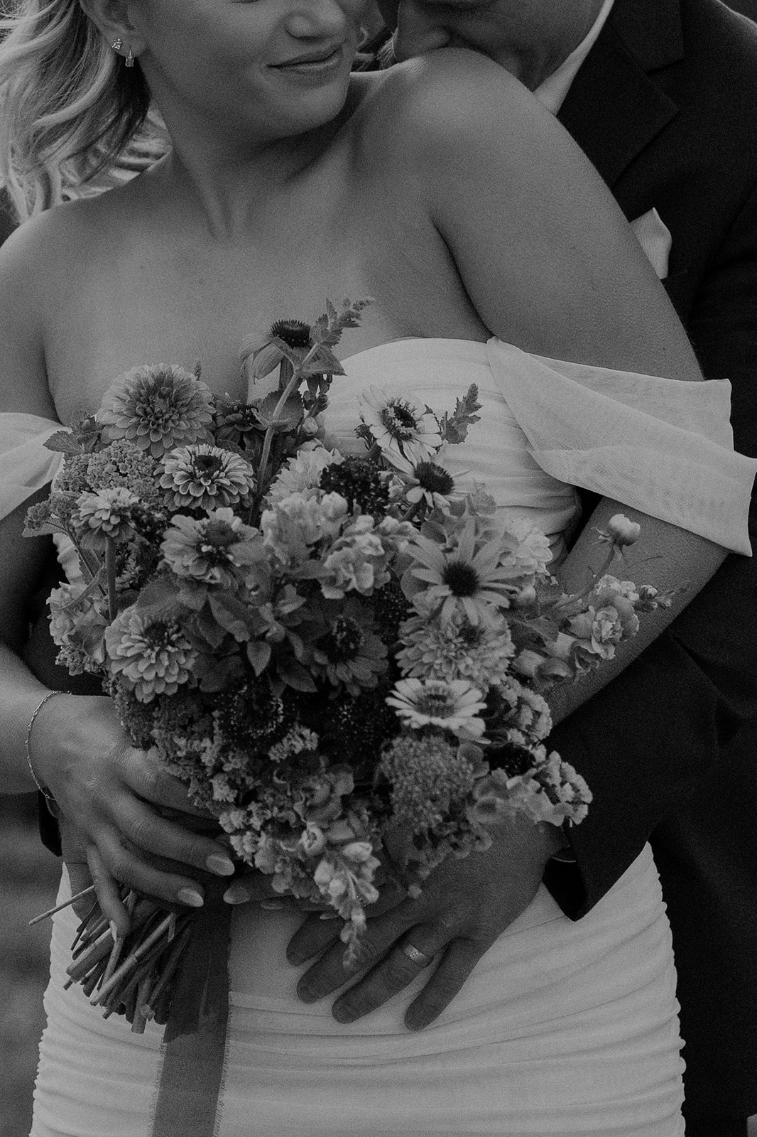 Close up black and white photo of a groom kissing his brides back