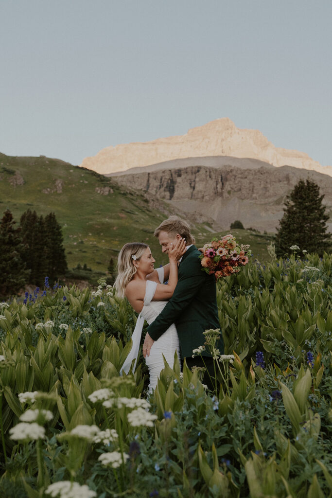 Bride and groom posing in the wildflowers of the San Juan mountains