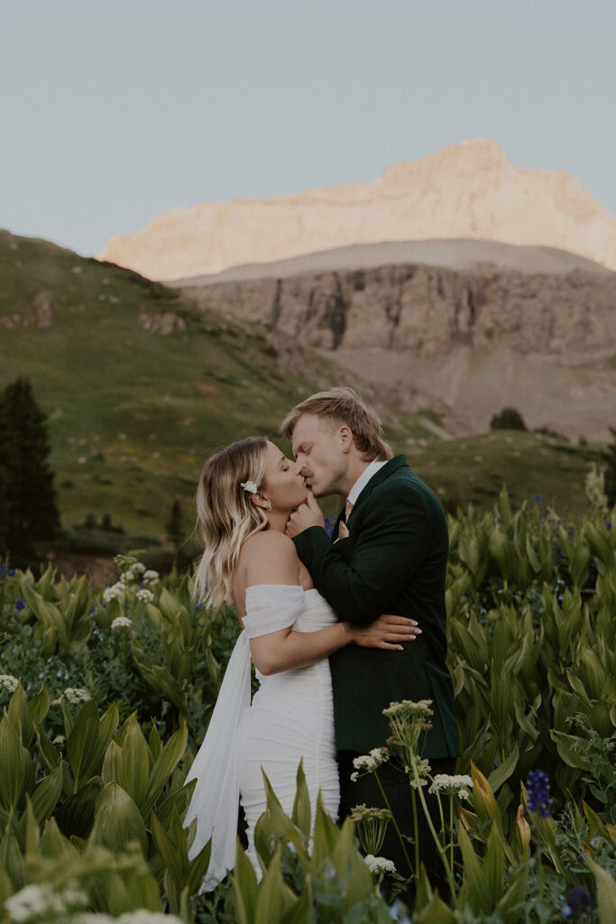 Bride and groom kissing in the wildflowers of the San Juan mountains