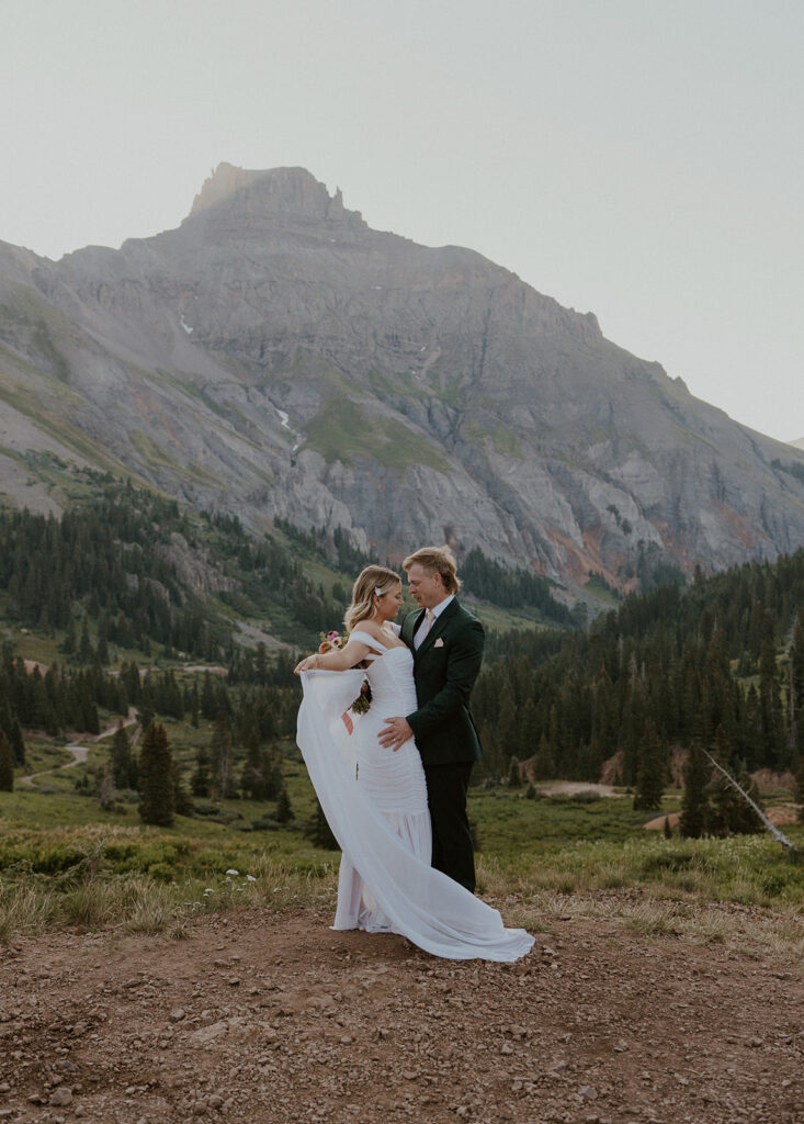 Bride and groom posing for their Colorado elopement photos with the San Juan mountains in the background