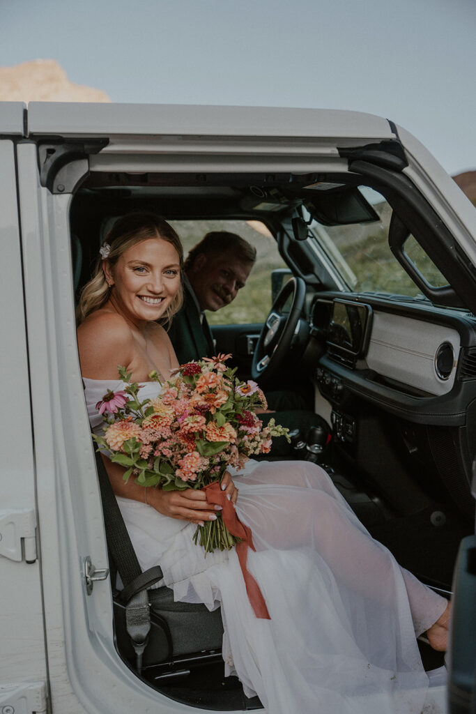 Bride and groom smiling in their jeep