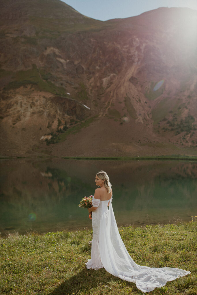 Bride posing in front of a lake during their San Juan Mountains elopement photos in Colorado