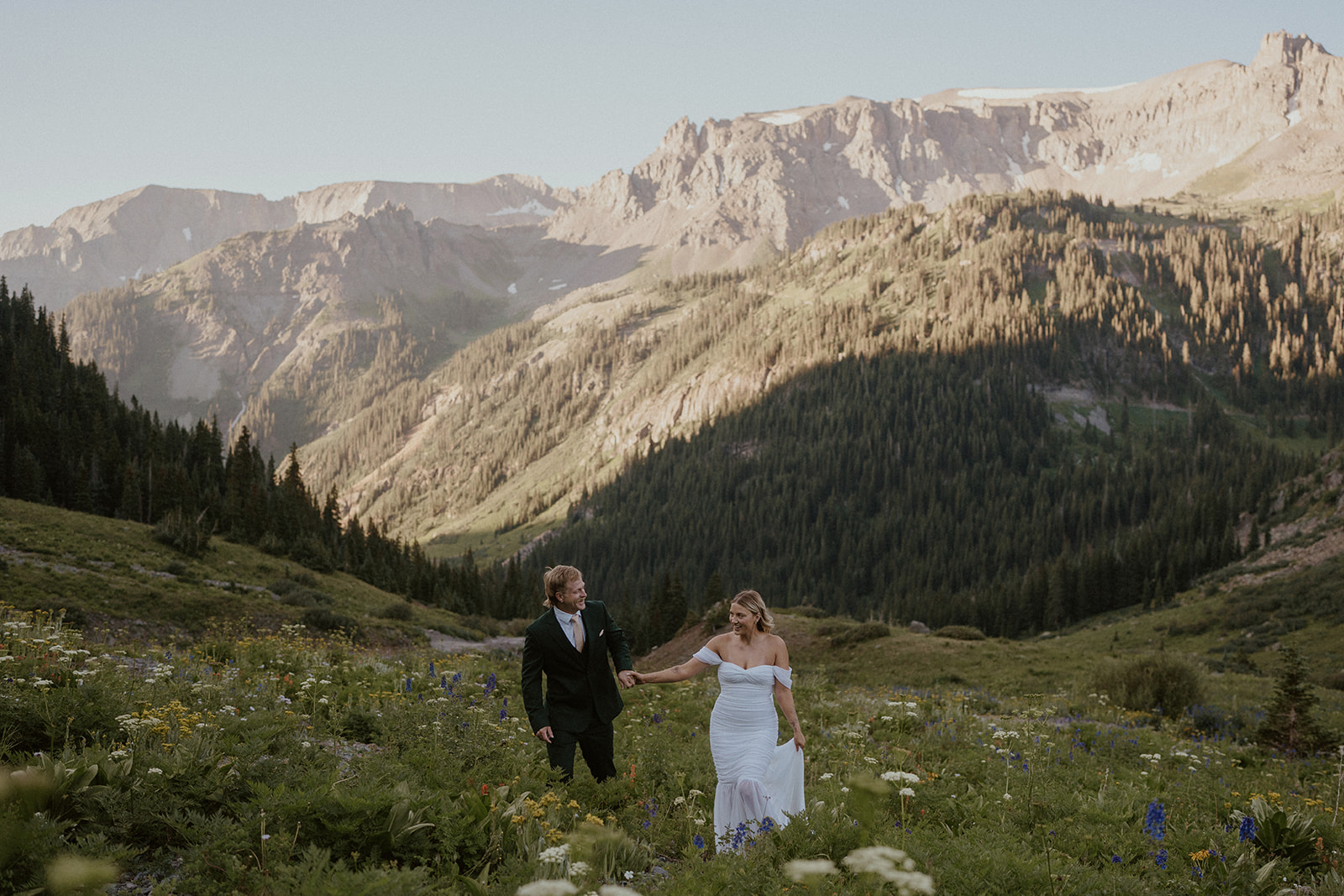 Bride and groom walking through the wildflowers for their San Juan mountains elopement photos in Colorado
