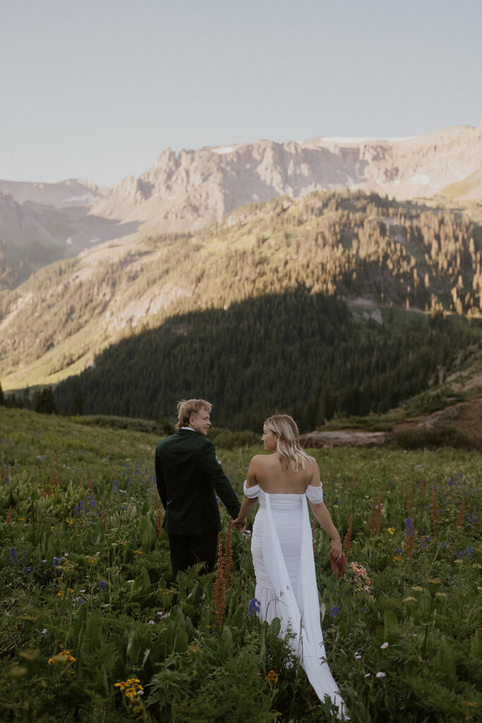 Bride and groom walking through the wildflowers for their San Juan mountains elopement photos in Colorado