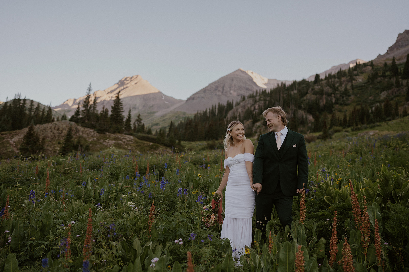 Bride and groom posing in a bed of wildflowers for their San Juan mountains elopement photos in Colorado