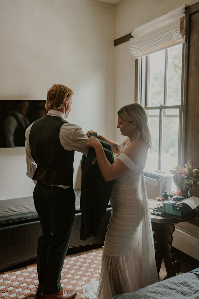 Bride helping the groom into his jacket