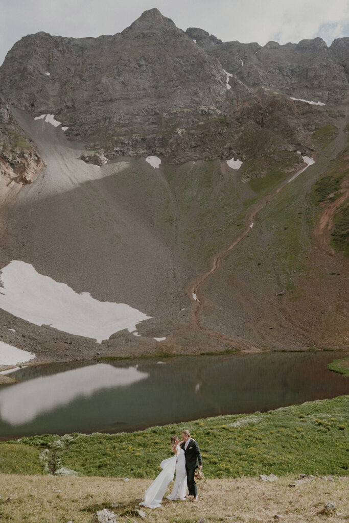 Bride and groom posing in front of a lake during their San Juan Mountains elopement photos in Colorado