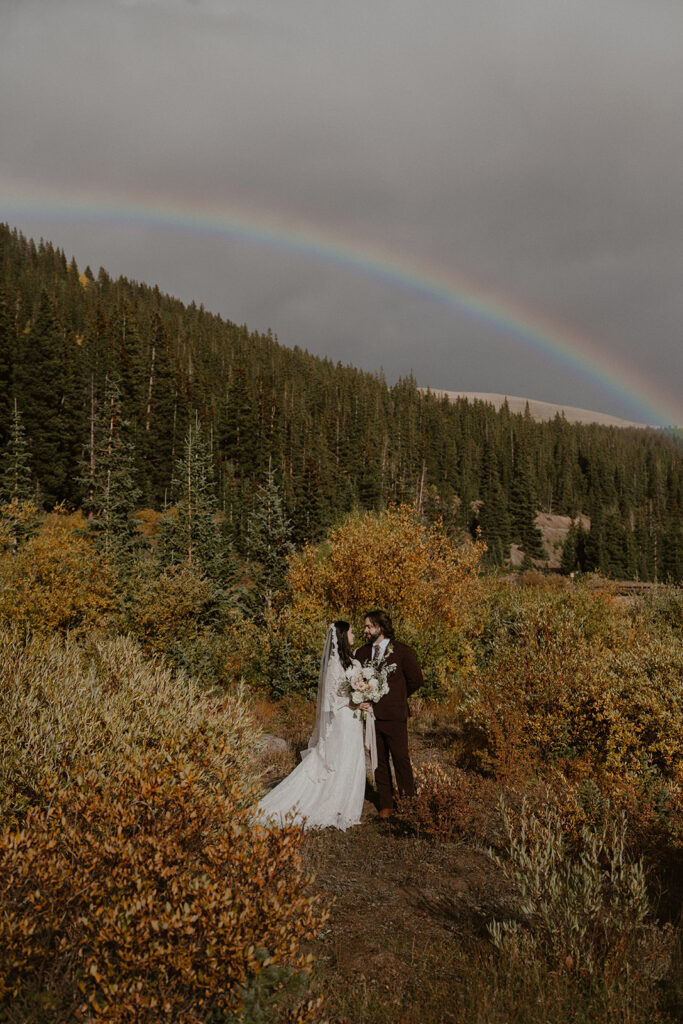 Fall elopement photos in the Colorado mountains with a rainbow overhead