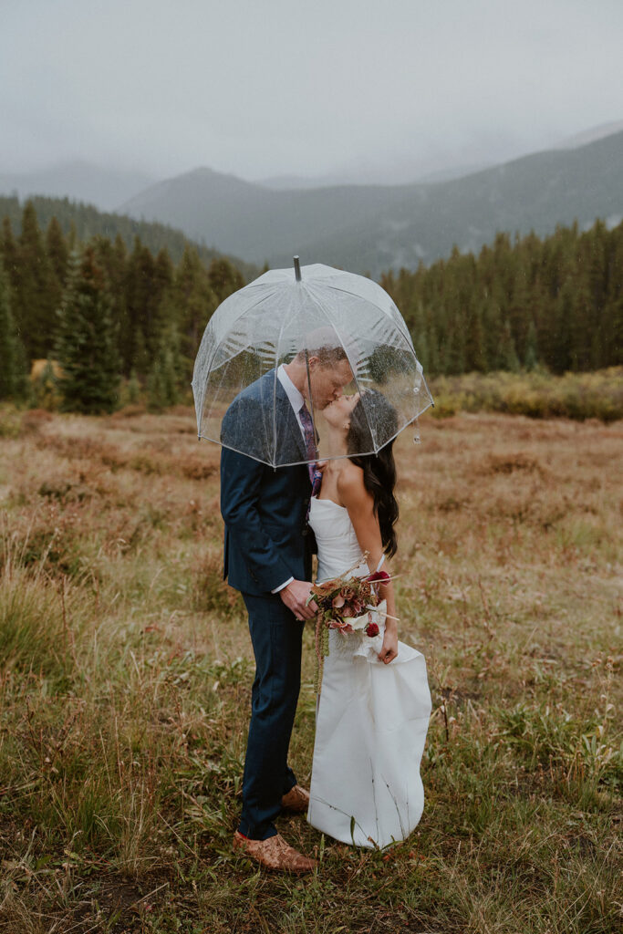 Rainy mountain bride and groom photos in Breckenridge, CO with clear umbrellas