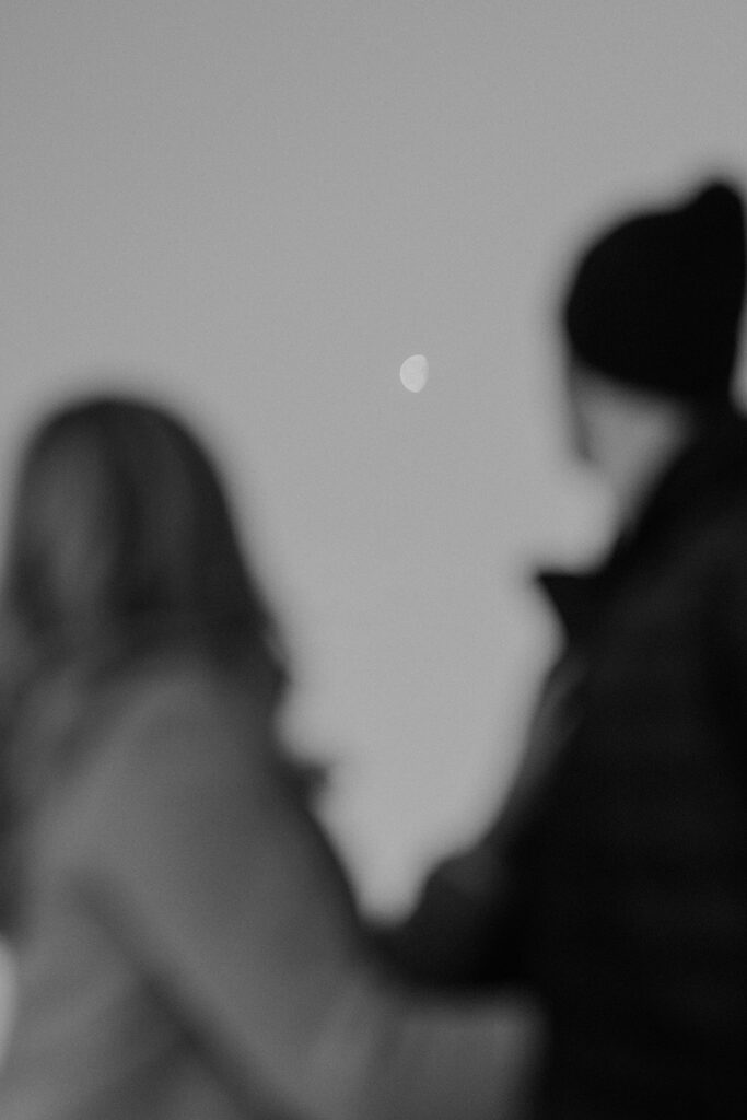 Couple looking up at the moon during sunrise